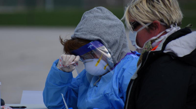 A health care worker rests her head on her hands at a testing location early in the pandemic. - (Justin Hicks/IPB News)