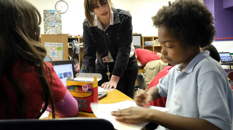 A teacher talks with students at Thomas Gregg Neighborhood School in Indianapolis. Indianapolis Public Schools announced that it is dropping limits on the number of absences employees could have in the spring of 2022 in order to qualify for retention bonuses that will be paid Sept. 9.   - Alan Petersime for Chalkbeat