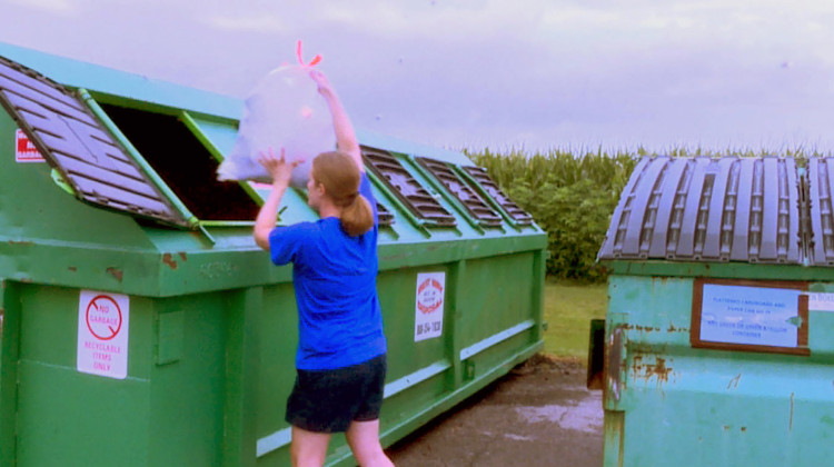 Amy Rather drops recycling into one of the bins behind the Johnson County Recycling District office. After July 31, this bin won't be available. - Rebecca Thiele/IPB News