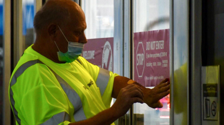 A worker at a Pilot Travel Center gas station in Greenfield, Indiana puts a stick on the door telling patrons not to enter if they feel symptoms associated with COVID-19. - Justin Hicks/IPB News