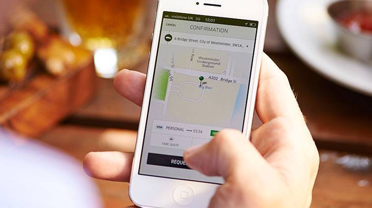 In this handout photo from Uber, a user confirms a ride request on his mobile phone. - Uber