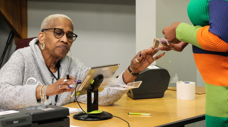 An election worker is handed a driver's license at check-in during early voting at the Indianapolis Library Pike Branch on Nov. 6, 2022. - Lauren Chapman/IPB News