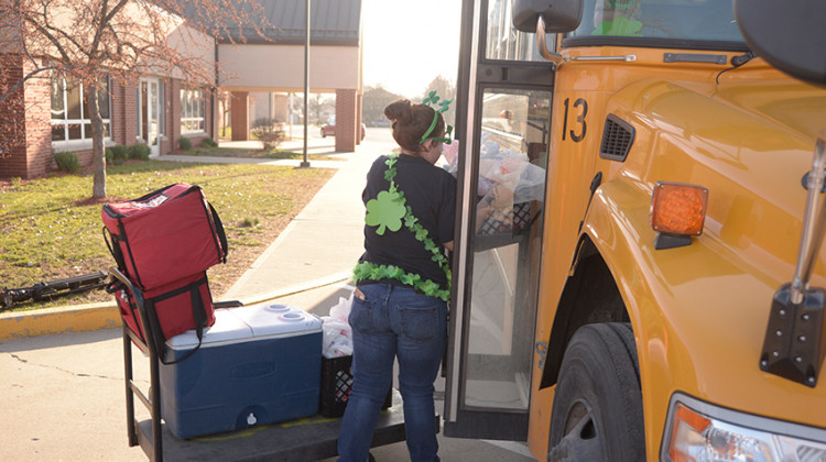 A Wayne Township Schools staffer loads cold meals into a bus for distribution to students on Tuesday, March 17, 2020 at Rhoades Elementary on Indianapolis' west side. - MSD Wayne Township Schools