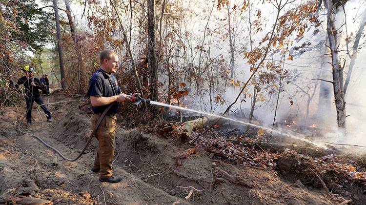 Assistant Chief Brent Masey, of Highway 58 Fire Department in Harrison, Tenn., sprays water on a wildfire Thursday, Nov. 10, 2016, in Soddy-Daisy, Tenn. - AP Photo/Mark Humphrey