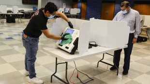 Joshua Lindl sanitizes a voting match as a voter casts his ballot in the Indiana primary in Indianapolis, Tuesday, June 2, 2020. Coronavirus concerns prompted officials to delay the primary from its original May 5 date. Nearly 550,000 voters requested mail-in ballots, more than 10 times the number of those ballots cast during the 2016 primary. - AP Photo/Michael Conroy