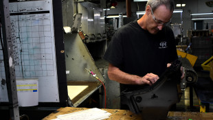 A worker at Decatur Plastic Products performs a final inspection on a piece that has just come off the assembly line. DPP specializes in molded plastic parts that are used in car dashboards and consoles. - Justin Hicks/IPB News
